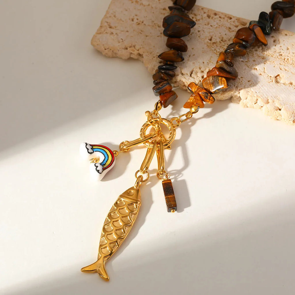 Bracelet with gold fish charm and rainbow charm on a light background