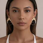 Woman wearing gold and black earrings against a neutral background