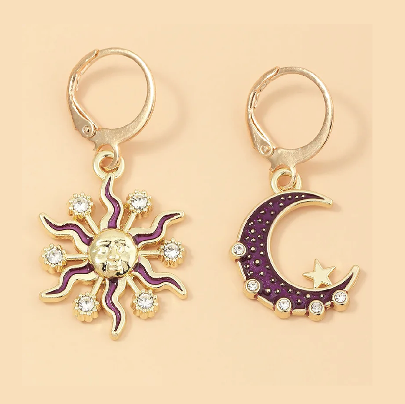 Sun and moon earrings with purple accents on a beige background