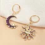 Gold earrings with purple accents shaped like a moon and sun on a beige background