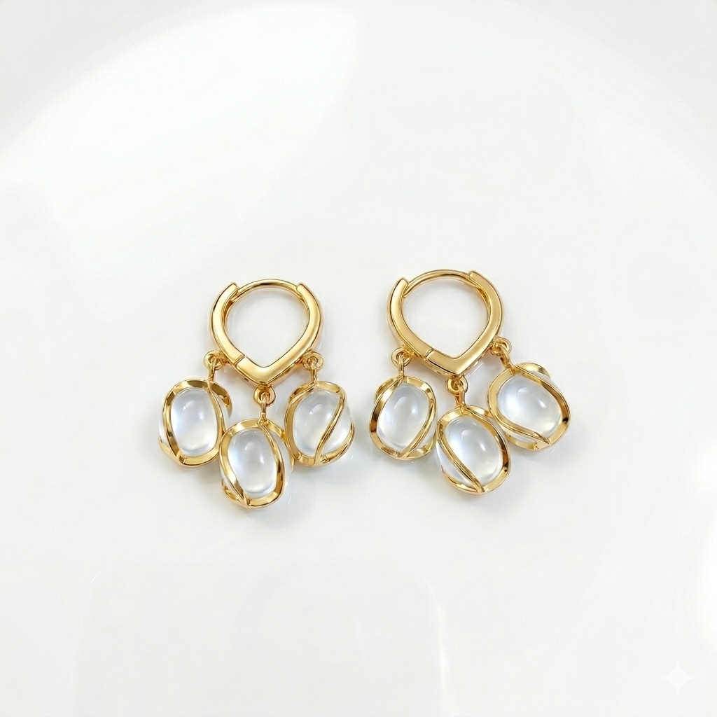 Gold earrings with white stones on a light gray background